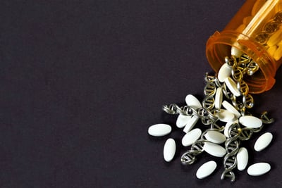 An image of a pill bottle spilling out medications and silver DNA strands